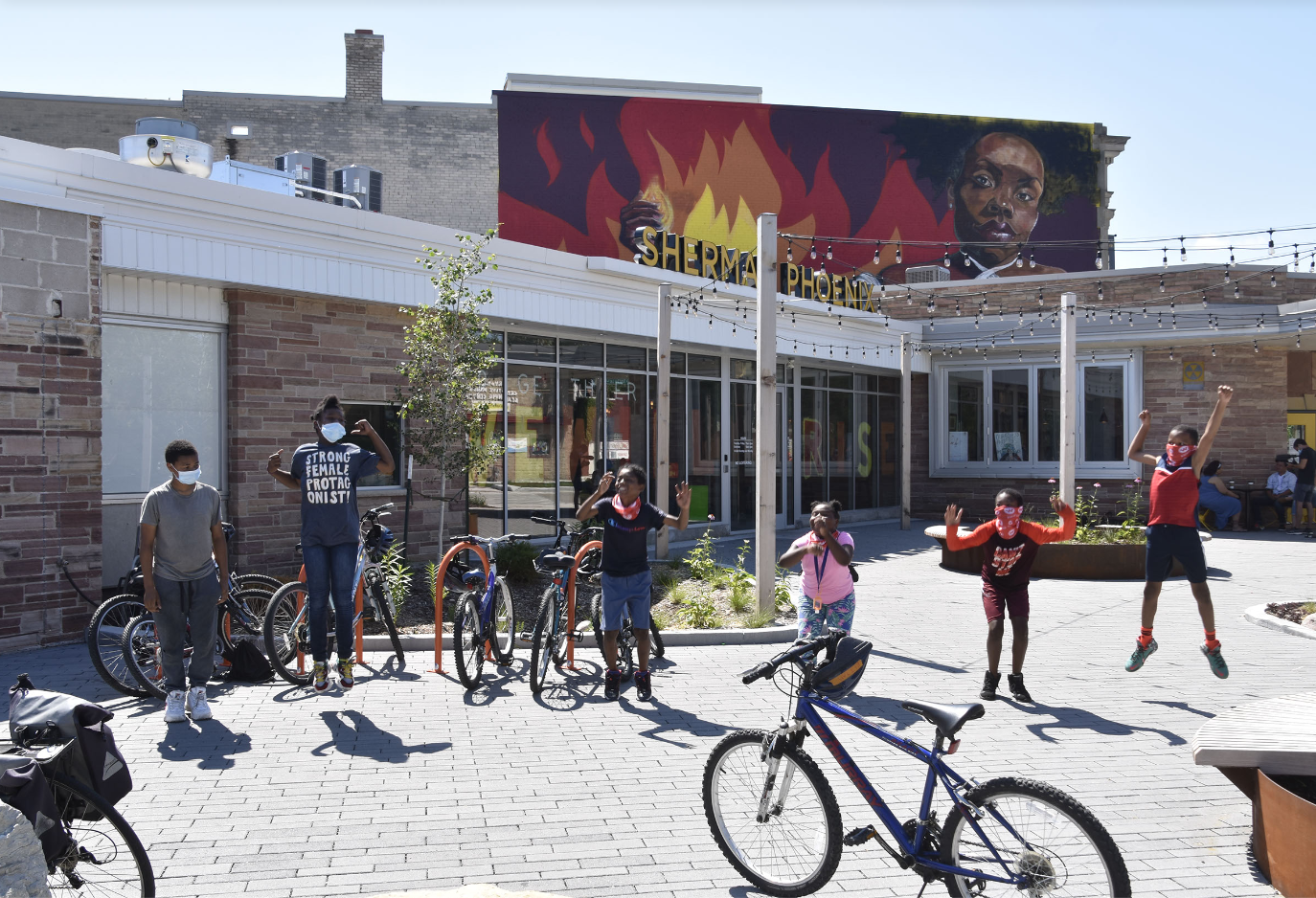 Milwaukee SRTS students stand near bikes and jump in the air.