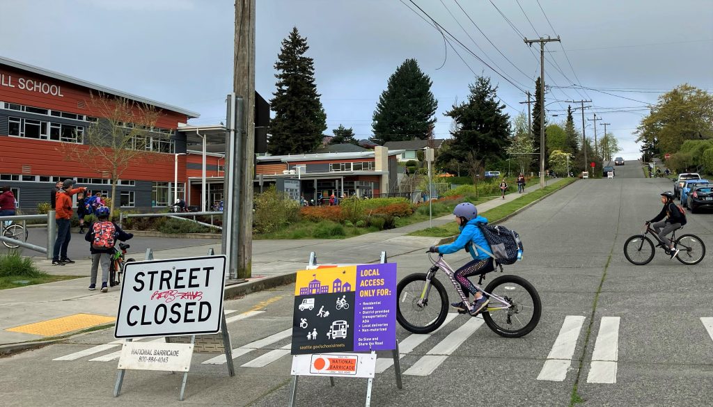 A young biker travels across a crosswalk and behind a "Street Closed" sign.
