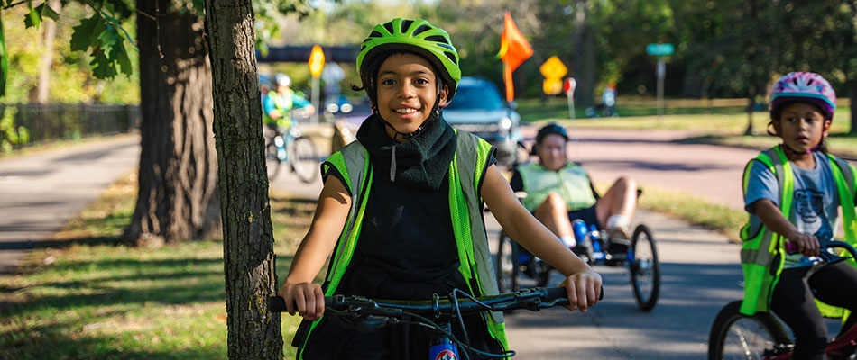 young person riding a bike on a tree lined sidewalk